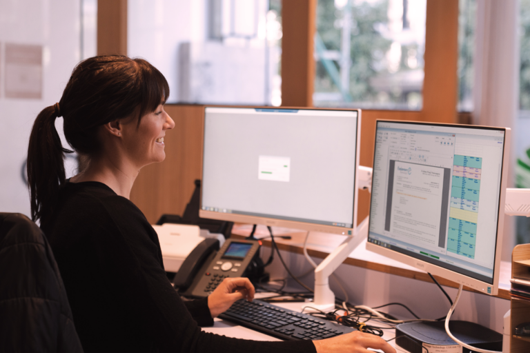 Practice manager working at a desk using software.